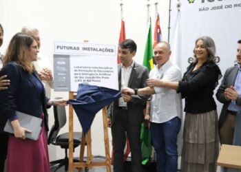 Imagem ilustrativa de laboratório tecnológico com professores e inteligência artificial em ambiente educacional.